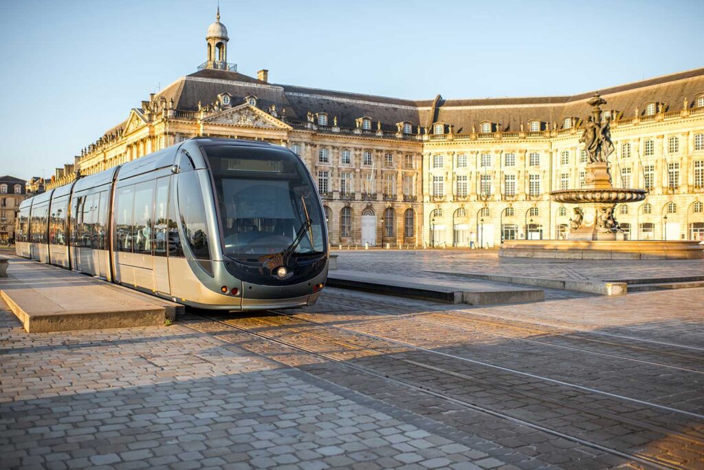 Modern tram in a historic European city square during sunset.
